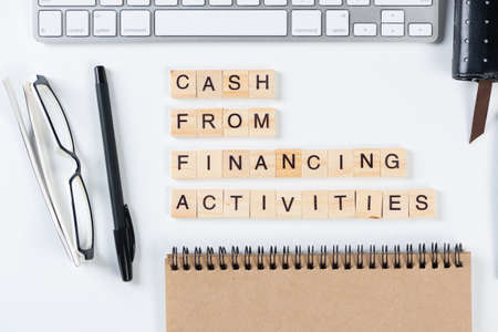 Cash from financing activities concept with letters. Still life of office workplace with supplies....