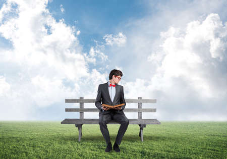 young student with a book. sits on a wooden benchの写真素材