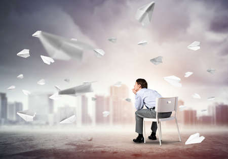 young businessman sits on an office chair, thoughtful and looking upの写真素材