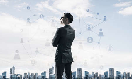 Young elegant businessman with arms crossed on chest looking awayの写真素材