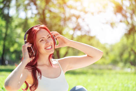 Young attractive woman listens to music in the park. Enjoying music in the park