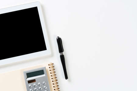 Still life of accountant workspace with office accessories. Flat lay white desk with tablet computer, calculator and notepad. Accounting and banking services. Finance and investment concept.の写真素材