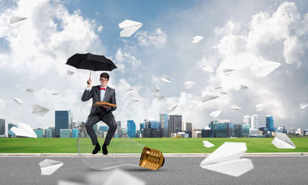 young businessman with umbrella and book, around fly in chaos paper planeの写真素材