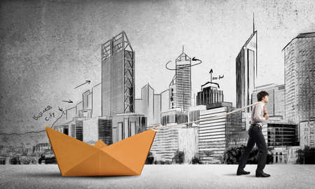 Successful businessman pulling with rope paper boatの写真素材