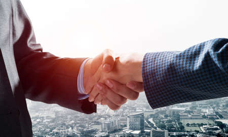 Close-up of the handshake of businessmen. Against the backdrop of the cityscapeの写真素材