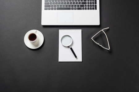 Still life of office workplace with cup of coffee and copy space. Flat lay black surface with laptop...