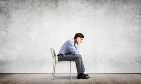 Businessman is sitting on an office chair with his head in his hands. Business stress and problemsの写真素材