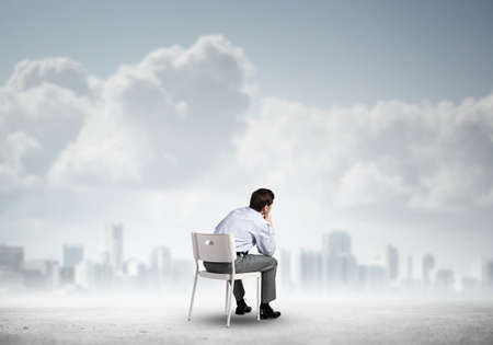young businessman sits on an office chair, thoughtful and looking upの写真素材