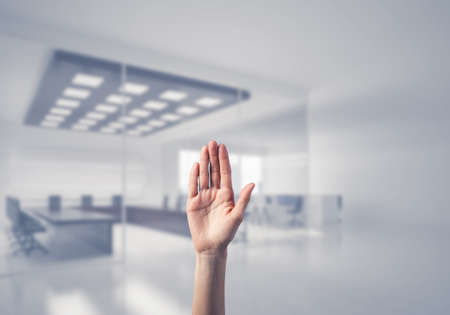 Close of woman hand touching screen with palm and office at backgroundの写真素材