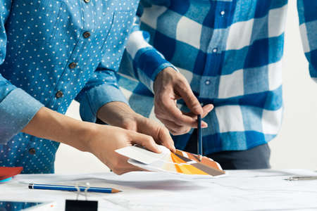 Interior designers discussing color samples for design project. Close up man hand with pencil...