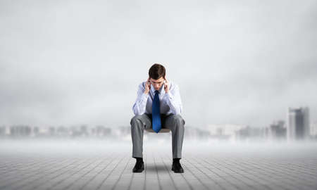 Businessman is sitting on an office chair with his head in his hands. Business stress and problems