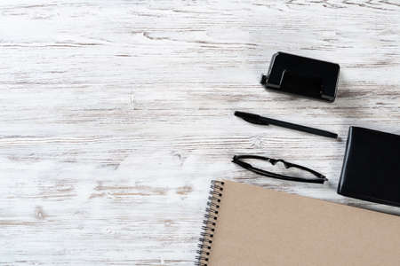 Still life of modern office workspace with supplies. Spiral notepad and paper hole puncher on white...