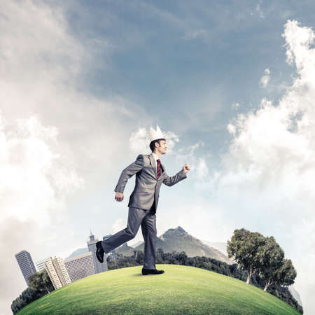 Young handsome businessman wearing white paper crown running in a hurryの写真素材