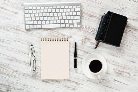 Still life of manager workplace in office with cup of coffee and supplies. Flat lay white wooden...