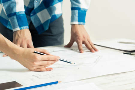 Design project discussing in architecture studio. Architect analyzing paper blueprint. Close up man...