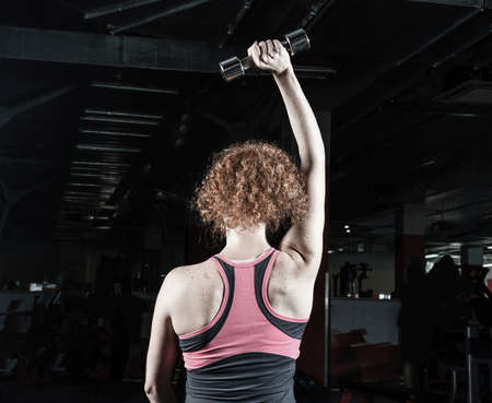 Woman bodybuilder engaged with dumbbells in the gym.の写真素材