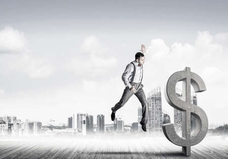 Young furious businessman going to crash with fist stone dollar symbolの写真素材