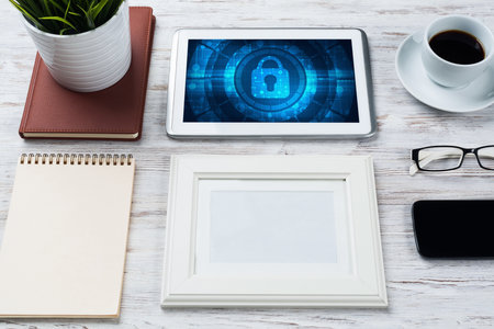 Business workplace with office stuff and tablet with padlock icons on screenの写真素材