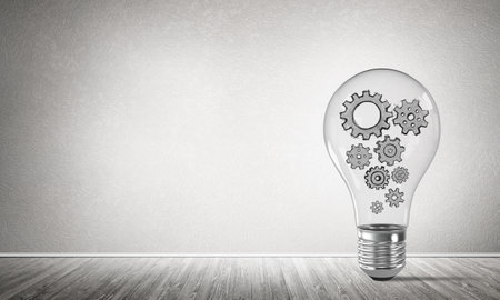Glass lightbulb with multiple gears inside placed in empty room with grey wall on background. 3D rendering.の写真素材