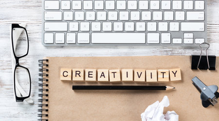 Creativity and innovation concept with letters on cubes. Still life of office workspace. Flat lay vintage wooden desk with computer keyboard and spiral notebook. Brainstorming and ideas generation.の写真素材