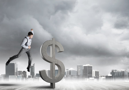 Young furious businessman going to crash with fist stone dollar symbolの写真素材