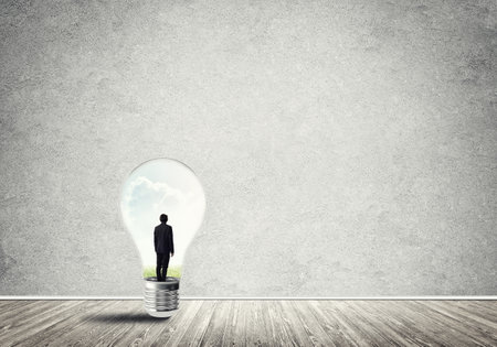 Businessman inside of light bulb in empty concrete roomの写真素材