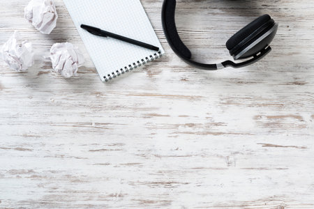 Still life of modern office workspace with copy space. Flat lay composition with headphones and spiral notepad on wooden surface. Time management and day planning. Corporate business workplaceの写真素材