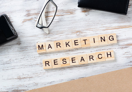 Marketing research concept with letters on cubes. Still life of office workspace with supplies. Flat lay grunge wooden desk with elegant glasses and notebook. Internet content marketing analysis.の写真素材