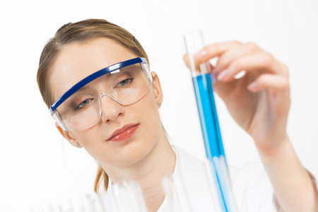 Pharmacology science laboratory research. Female scientist in protective goggles holding test tube...