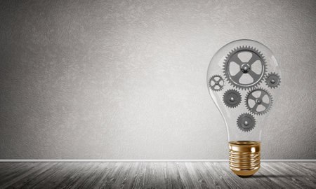Glass lightbulb with multiple gears inside placed in empty room with grey wall on background. 3D rendering.の写真素材