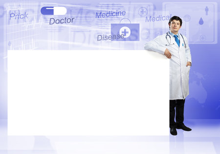 Young handsome doctor with white blank banner. Place your textの写真素材