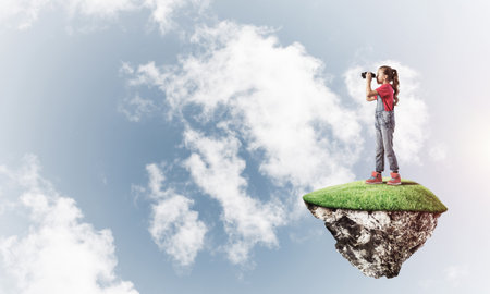 Cute smiling girl sitting on floating island high in skyの写真素材