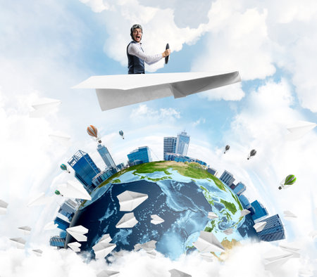 Businessman in aviator hat sitting in paper plane and holding steering wheel. Pilot driving paper plane in cloudy blue sky. Spherical view of modern city with high skyscrapers and sea line.の写真素材