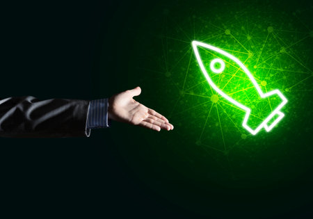 Rocket glowing icon and businessman hand on dark backgroundの写真素材