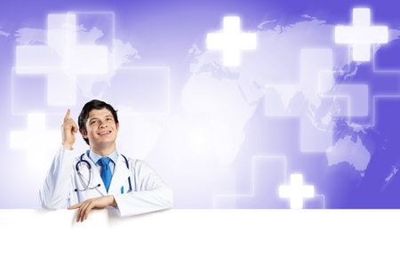 Young handsome doctor holding white blank banner. Place your textの写真素材
