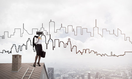 Faceless businesswoman with camera zoom instead of head standing on house roofの写真素材