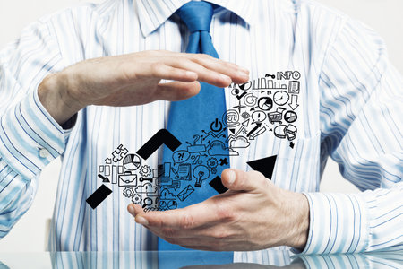 Businessman in suit sitting at desk making protective gesture with palmsの写真素材