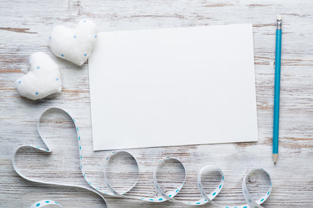 Flat lay composition with white love hearts and ribbon. Blank sheet of white paper on vintage wooden table. Declaration of love letter. Saint Valentines day congratulation. Romantic event invitation.の写真素材