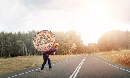 Builder man carrying on his back big cent coinの写真素材