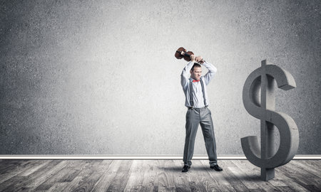 Young furious businessman going to crash with violin stone dollar symbolの写真素材