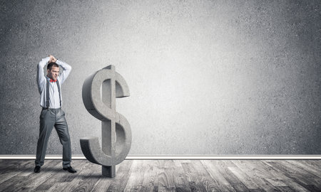 Young furious businessman going to crash with hands stone dollar symbolの写真素材