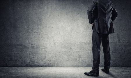 Back view of confident businessman in empty concrete roomの写真素材