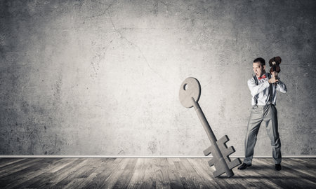Determined businessman in concrete interior breaking with violin stone key figureの写真素材