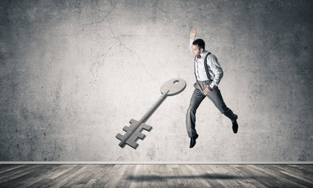 Determined businessman in empty interior breaking with fist stone key figureの写真素材