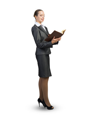 A businesswoman in a business suit stands with an open diary in her hands. On a white backgroundの写真素材