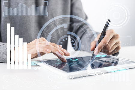 Businessman hand touching virtual screen flying above digital tablet. Online project management and financial diagrams visualization. Modern business innovation and intelligence technology.の写真素材