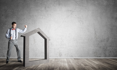 Determined businessman going to break with fist house concrete figureの写真素材