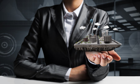 Cropped image of businessman in suit presenting in his hand modern city block with office view on background. 3D rendering.の写真素材