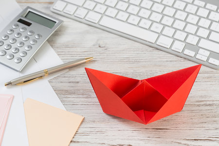 Businessman workspace at office desk with red paper ship. Flat lay table with calculator, business reports and pen. Close up red origami boat. Creative and innovative solution for business.の写真素材