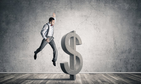 Young furious businessman going to crash with fist stone dollar symbolの写真素材